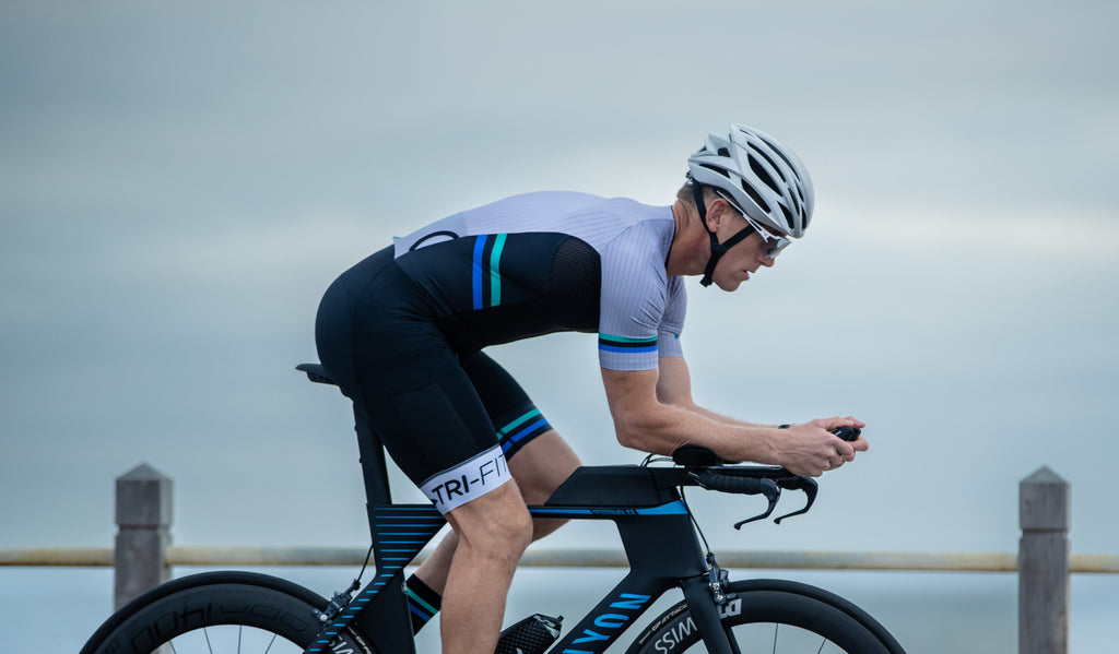 Man wearing EVO IRON Tri Suit cycling on a bridge